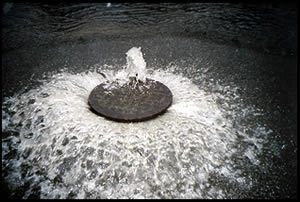 Photo of a manhole cover blown off by June 2006 sewer overflow in Rhode Island.
