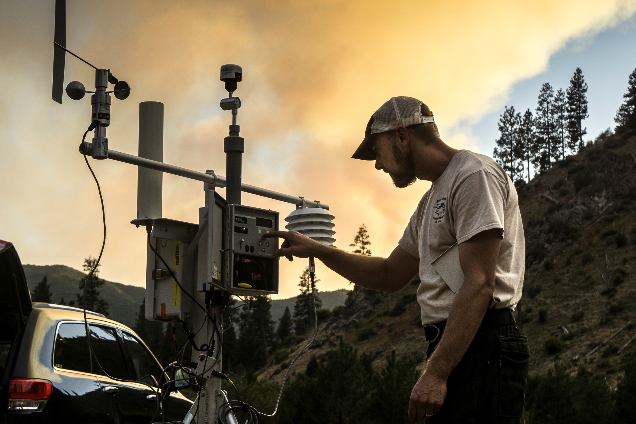 Person installing emergency PM2.5 monitor with smoke plume in the background.